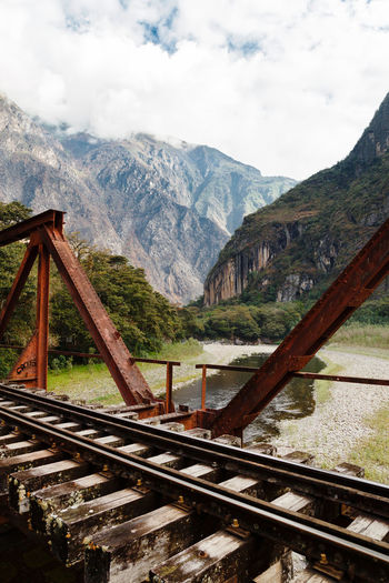 Railroad tracks by mountains against sky