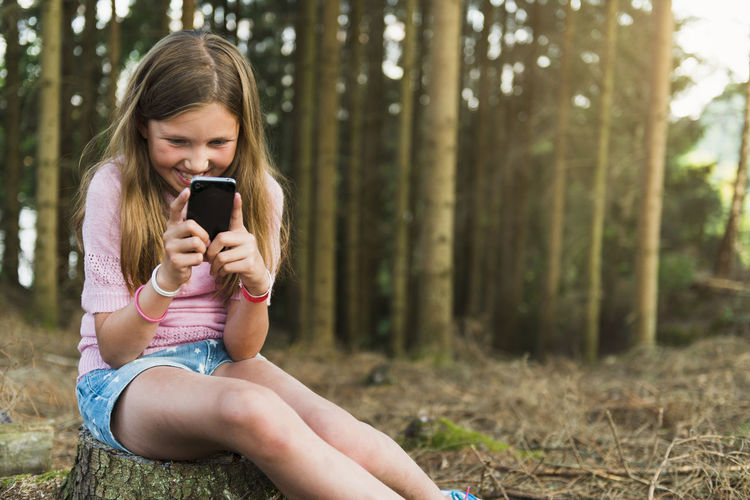 Girl with cell phone at forest