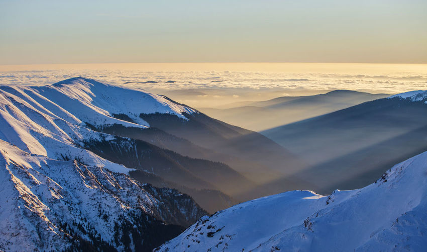 Scenic view of snow covered mountains during sunset