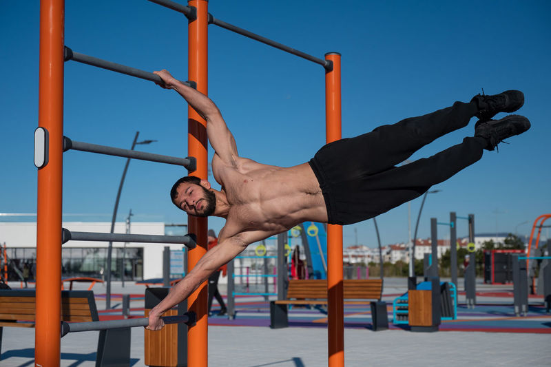 Low angle view of young woman exercising at playground
