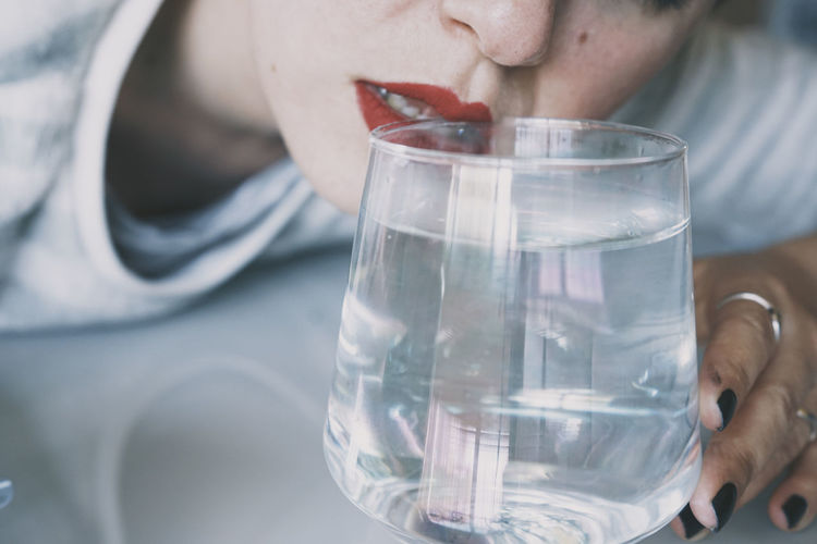 Close-up of woman holding glass of water