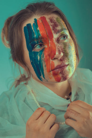 Young woman with painted face against wall