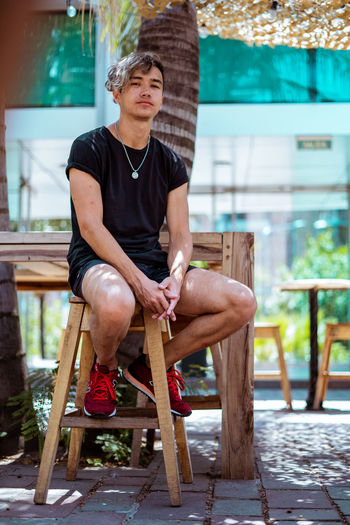 Young man sitting on chair, summertime restaurant outdoors.