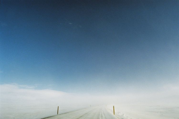 Tire tracks on road against sky during winter