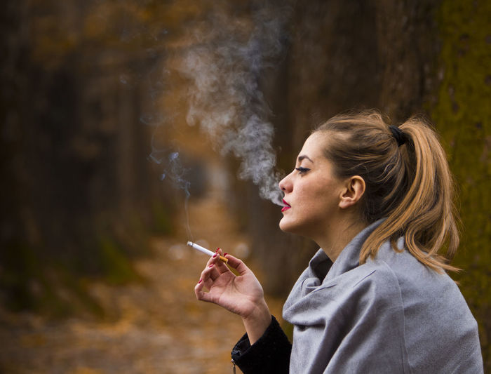 Side view of woman smoking outdoors