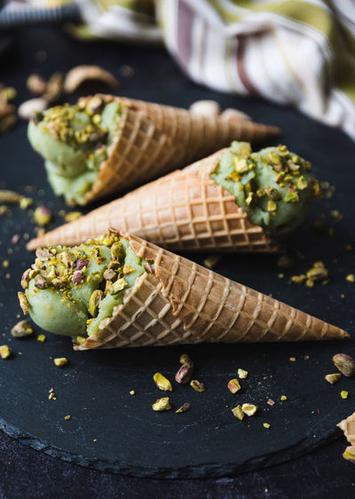 Close up of pistachio ice cream in cones on black background.