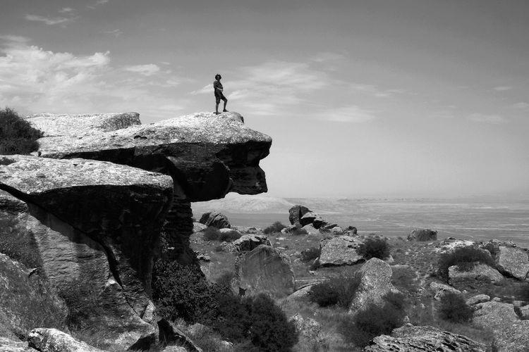 Man standing on cliff against sky