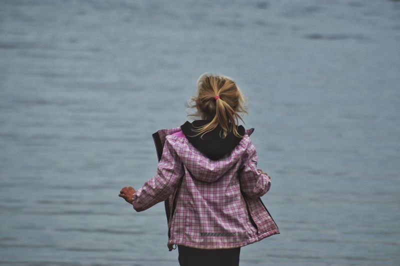 Rear view of girl standing against sea at beach