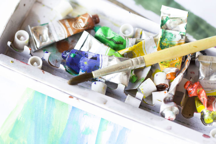 High angle view of paintbrush with oil paint tubes