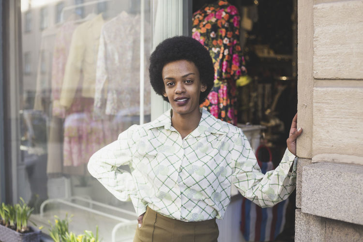 Portrait of female entrepreneur with hand on hip standing outside boutique