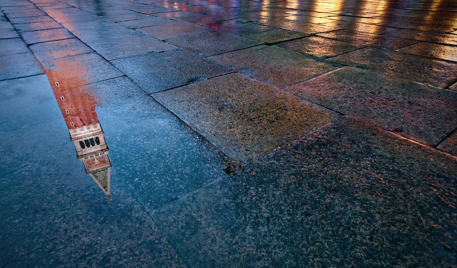Reflection of tower on puddle in piazza san marco