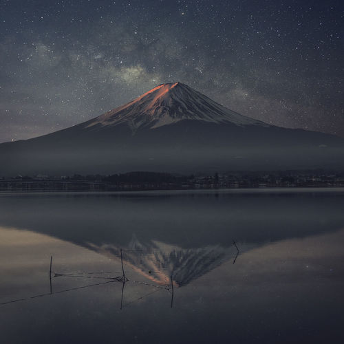 Reflection of snowcapped mountains in lake against sky at night