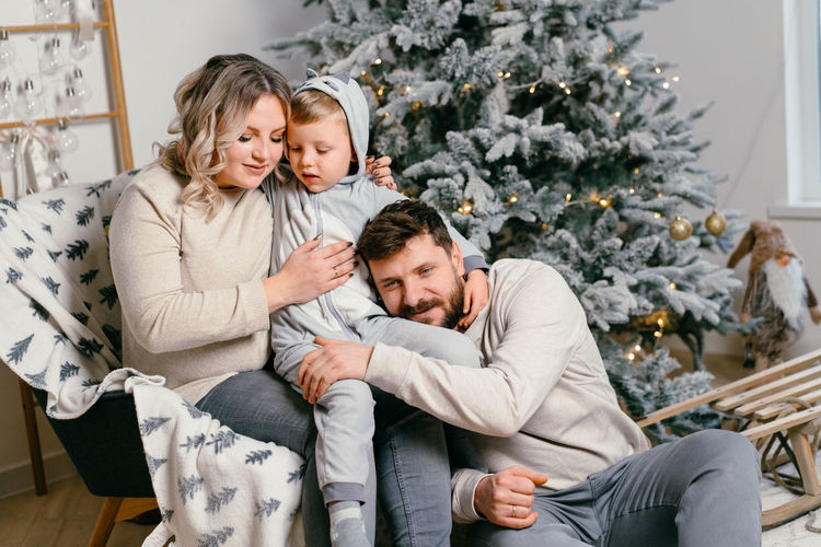 Cheerful family sitting by christmas tree