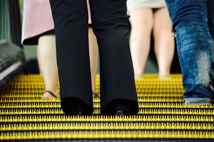Low section of people standing on escalator