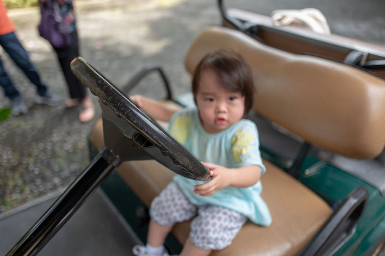 Portrait of cute girl sitting on golf cart