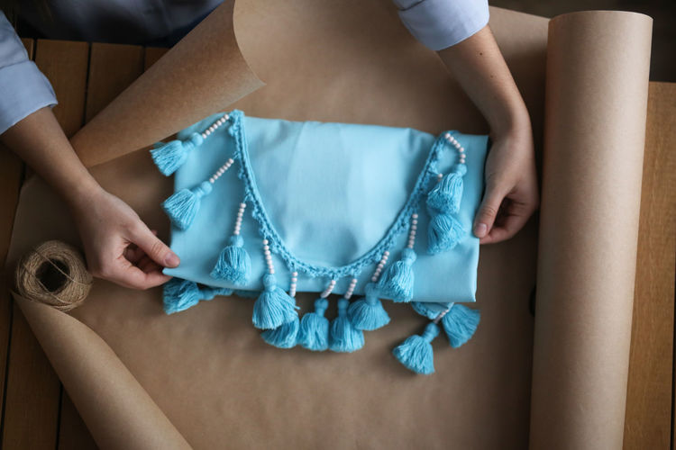 Handmade dress in paper packaging, the girl wraps the dress. concept of hobby, order to the buyer