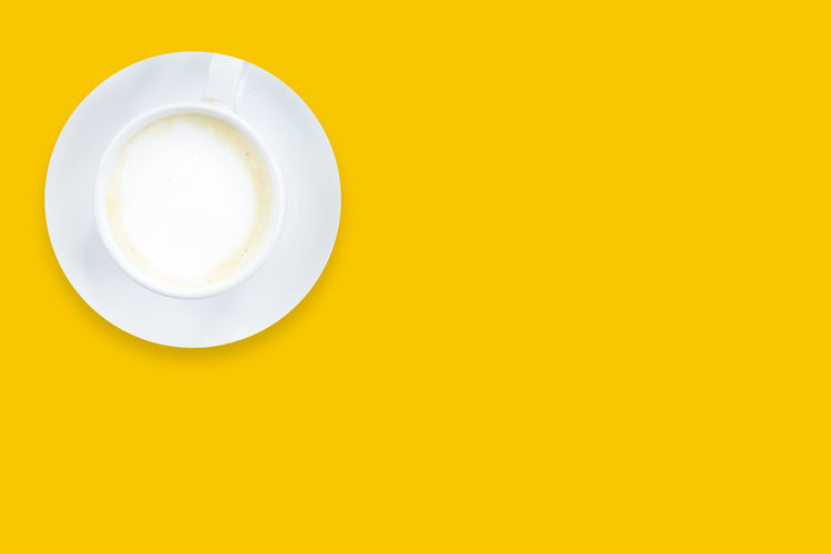 Directly above shot of coffee cup against yellow background