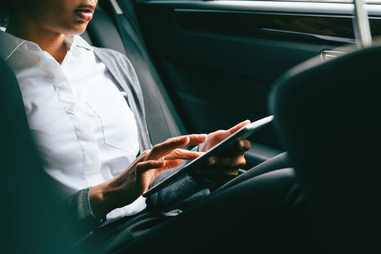 Midsection of woman using tablet while sitting in car