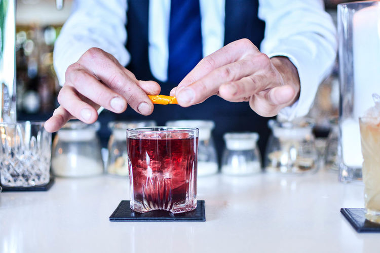 Midsection of bartender preparing a negroni at restaurant