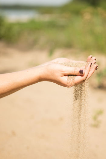 Midsection of woman hand on sand