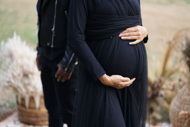 Maternity photo with rocker outfit theme in black and hands holding belly
