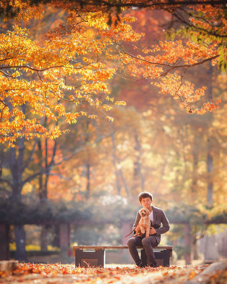 Side view of man sitting on field during autumn