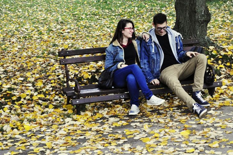 Couple sitting in park during autumn