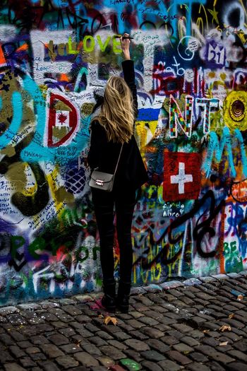 Rear view of woman painting on john lennon wall