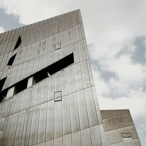Low angle view of modern building against cloudy sky