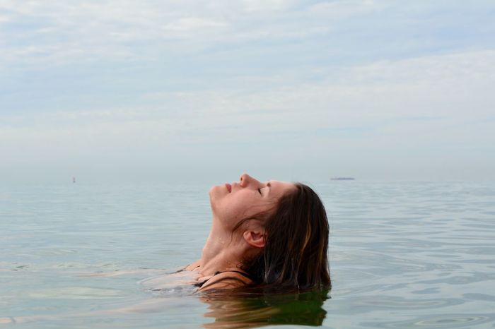 Close-up of woman swimming in sea against sky