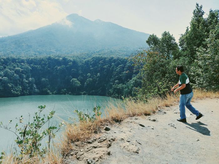 Side view of man in lake against mountains