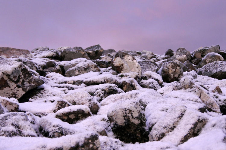 Snow covered rocks against a pink morning sky