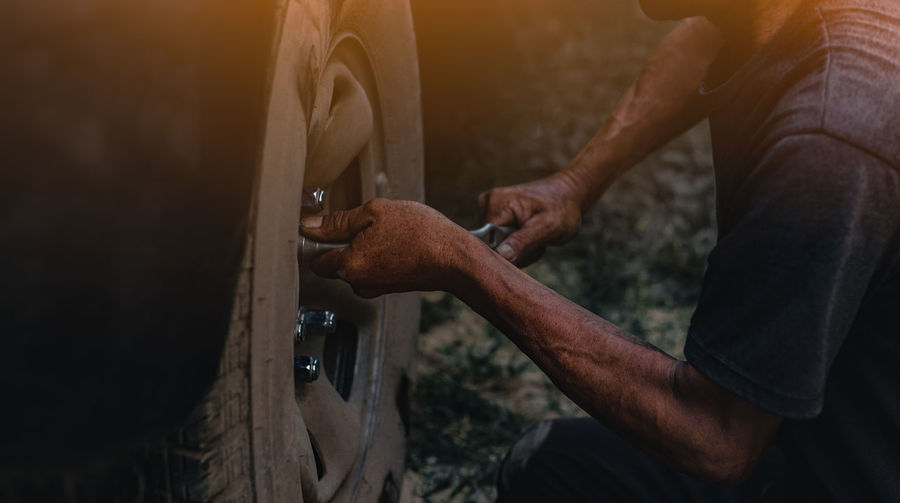 Midsection of man changing car tire