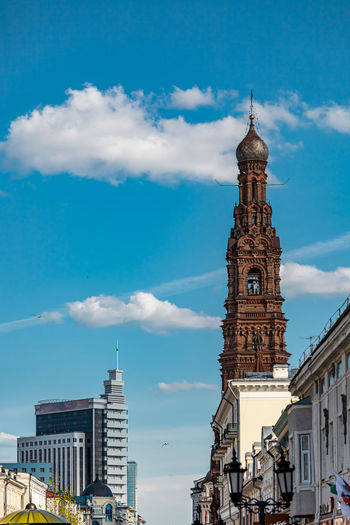 Clock tower amidst buildings in city against sky