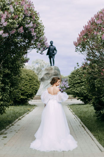 A beautiful delicate elegant woman bride in a wedding dress walks alone in a spring outdoor park