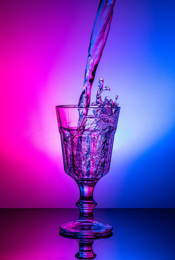 Water splashing on glass against blue background