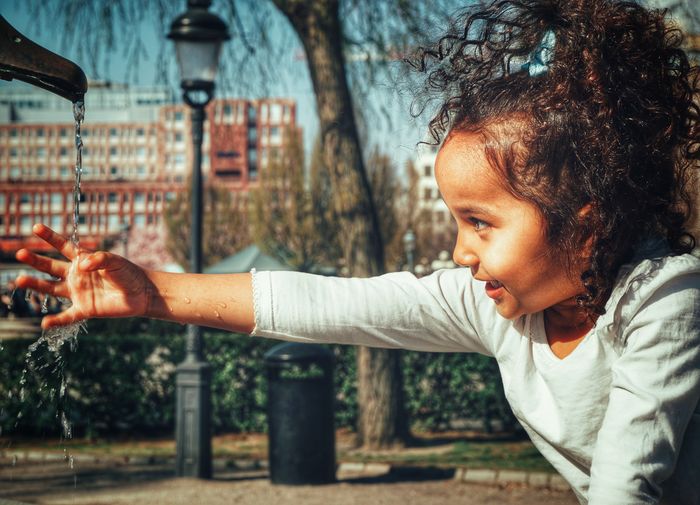 Cute girl touching running water in park