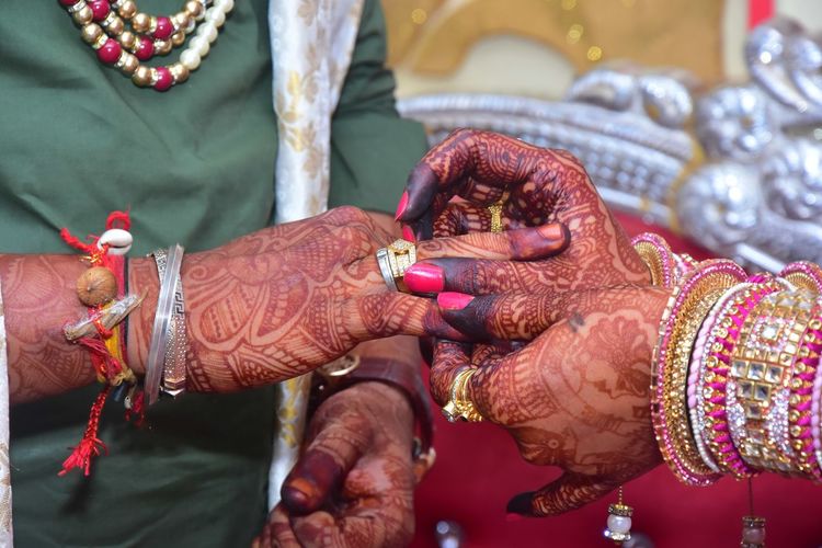 Midsection of couple holding rings in wedding ceremony