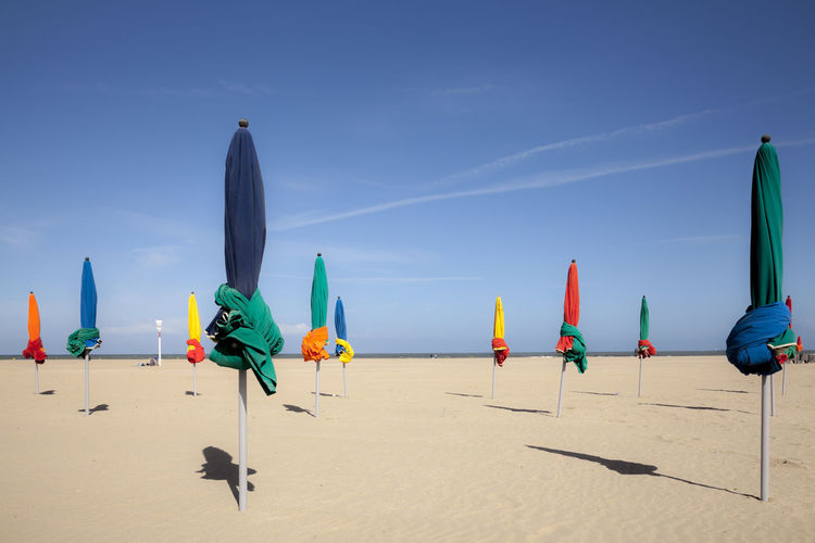 Colorful umbrellas at beach against blue sky