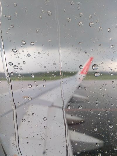 Close-up of waterdrops on glass against airplane window