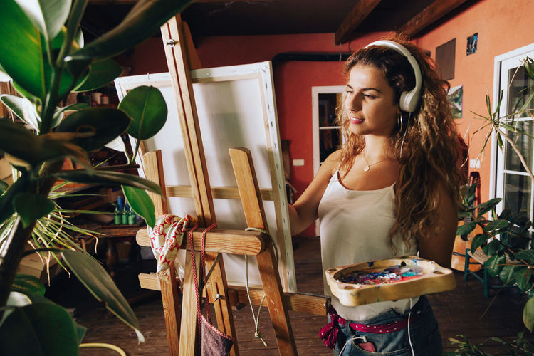 Young woman painting on easel