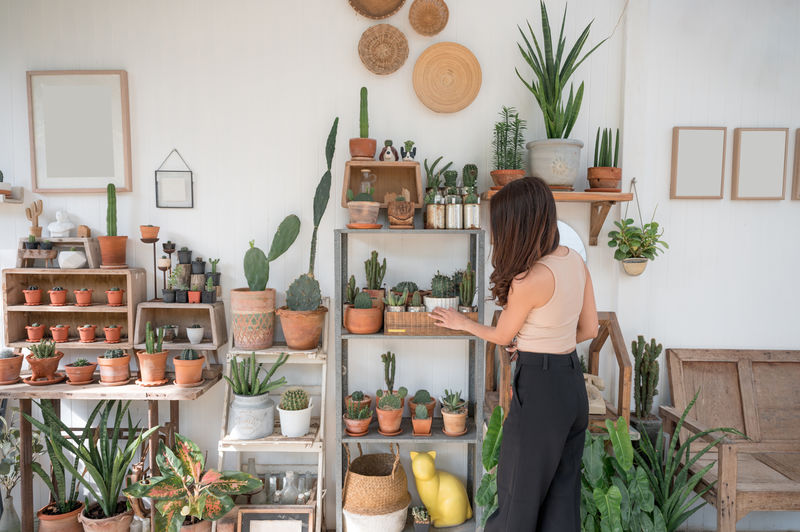 Rear view of woman standing by potted plants in store