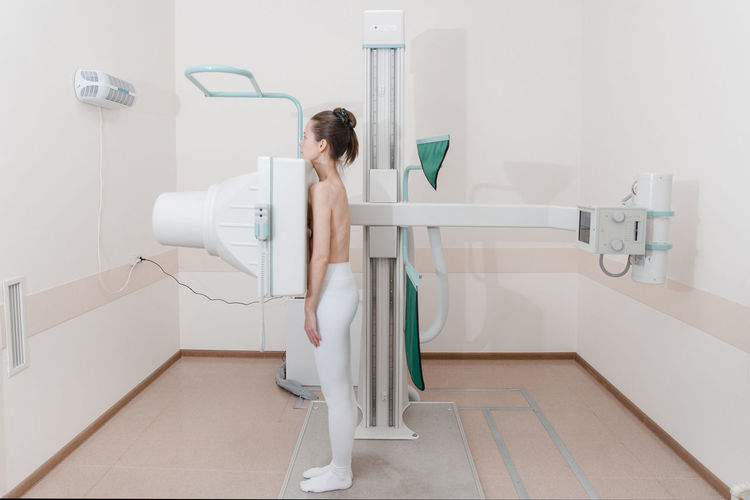 Side view of woman standing by scanning machine at clinic