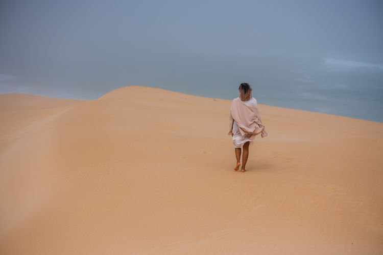 Woman walking alone along sand dune