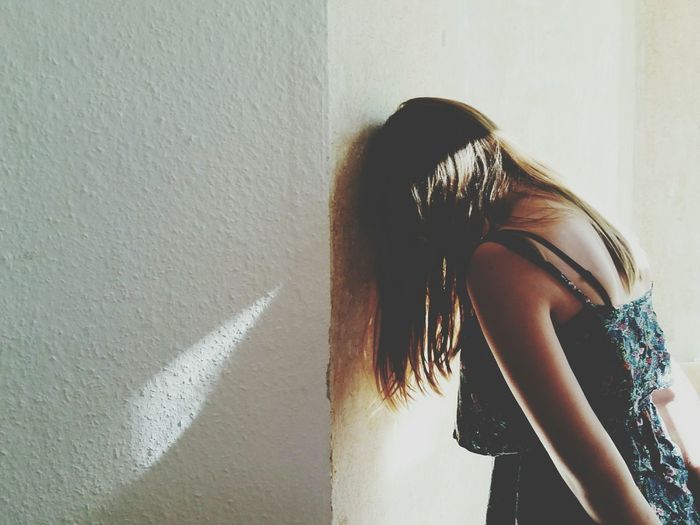 Side view of depressed woman leaning head on white wall
