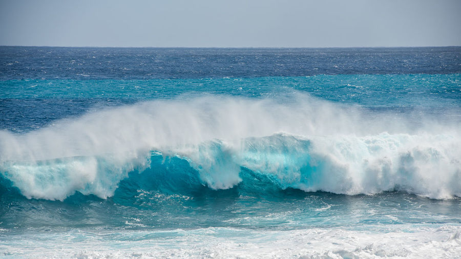 Waves splashing in sea against sky