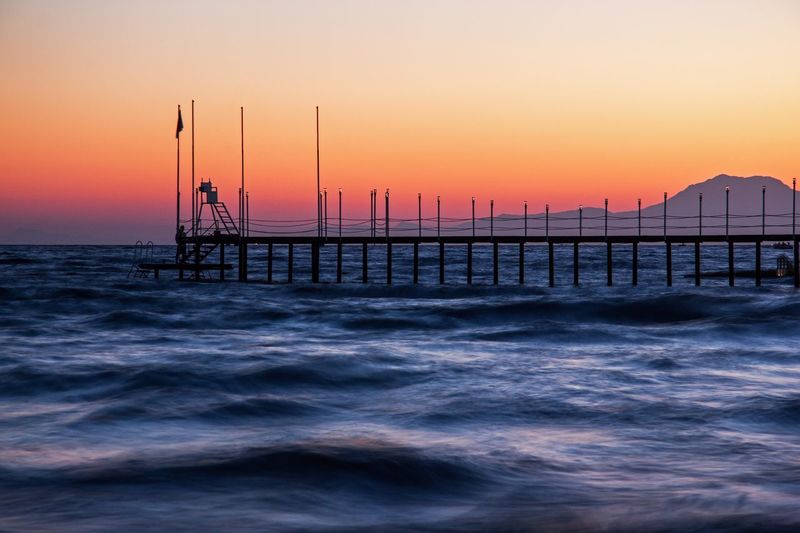 Scenic view of pier against sunset
