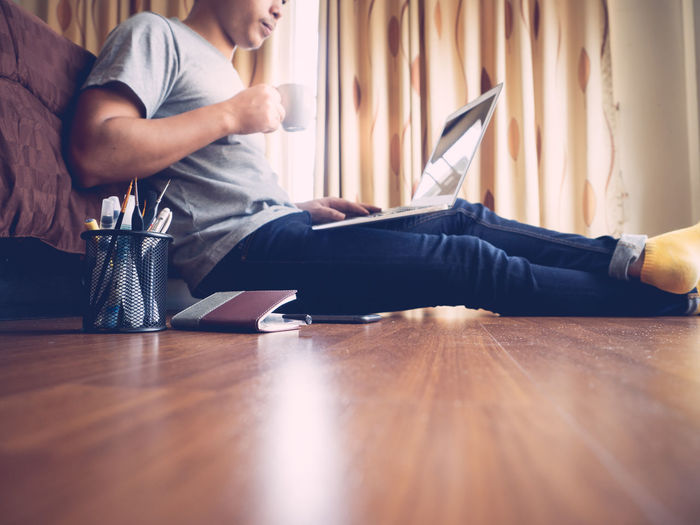 Man using laptop while sitting on floor at home