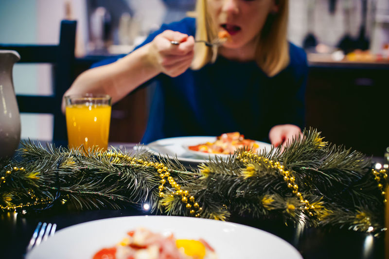 Midsection of woman eating food at home during christmas