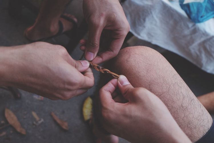 Low section of men braiding leather